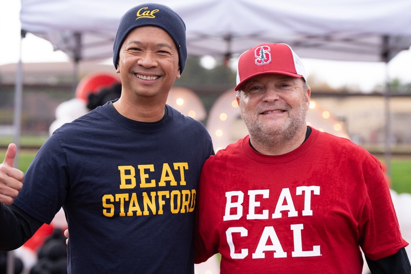 Two fans stand side by side, one in a “Beat Stanford” shirt and the other in a “Beat Cal” shirt.