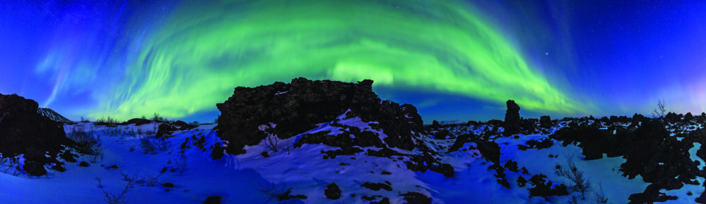 A snowy mountain with green northern lights in the sky