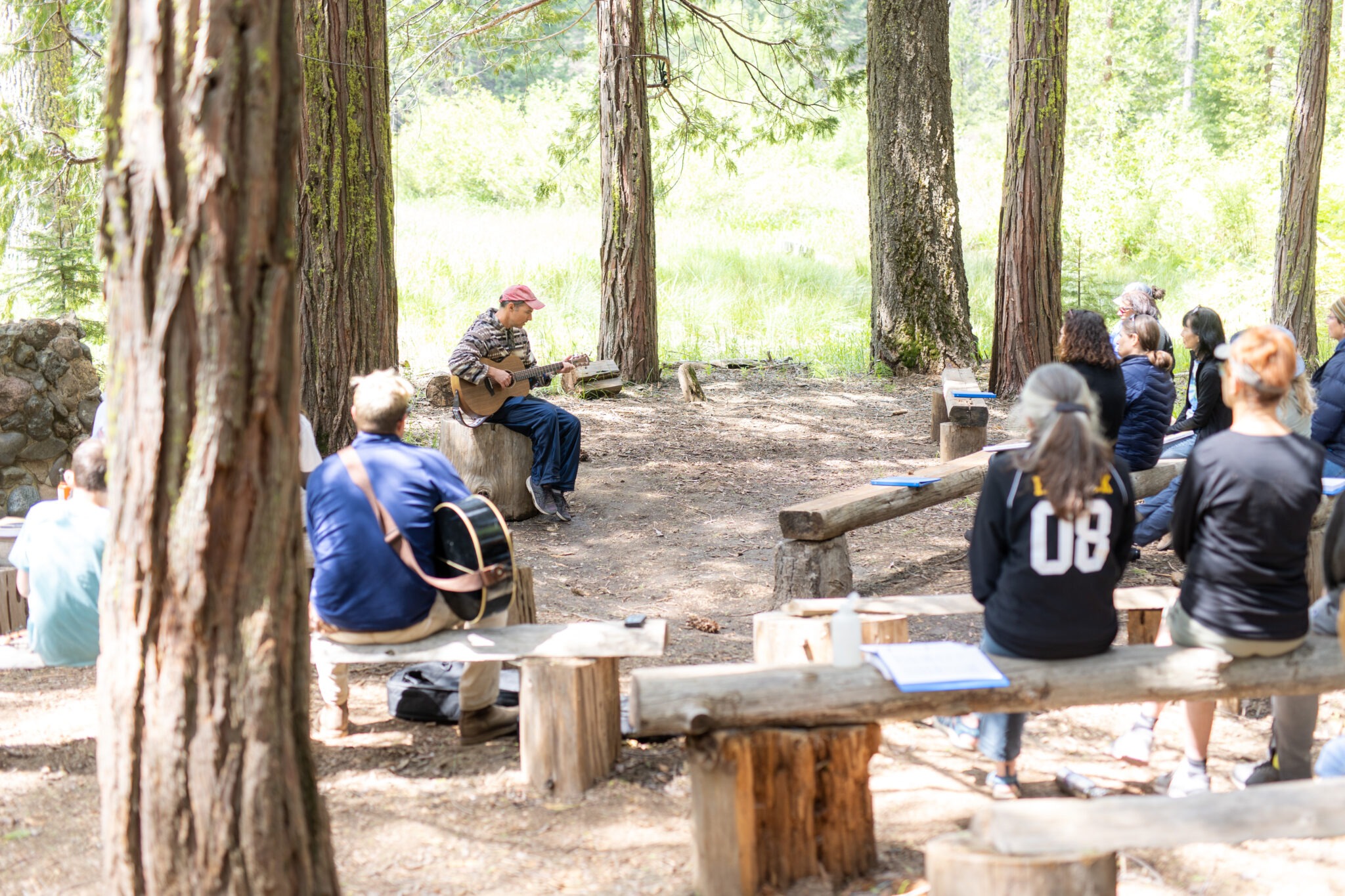 A camp attendee plays guitar to a gathering at Creekside. Photo by Kevin Kitsuda.