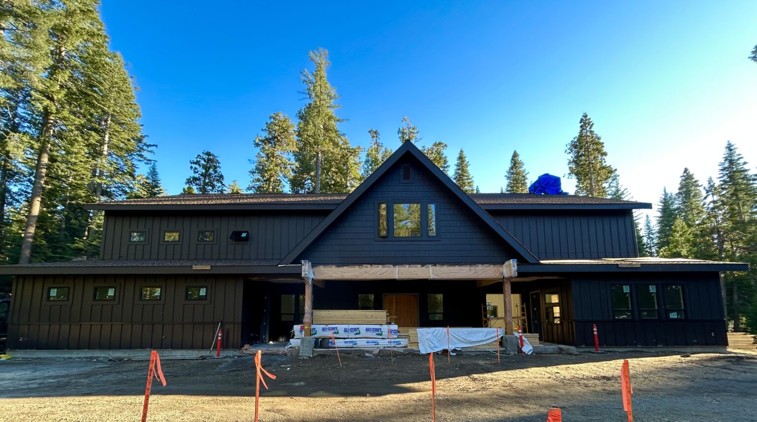 A photo of the front of the new Lair Lodge at Camp Oski, with trees in the background and blue skies above